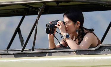 A tourist using binoculars to view wildlife Tanzania jpg